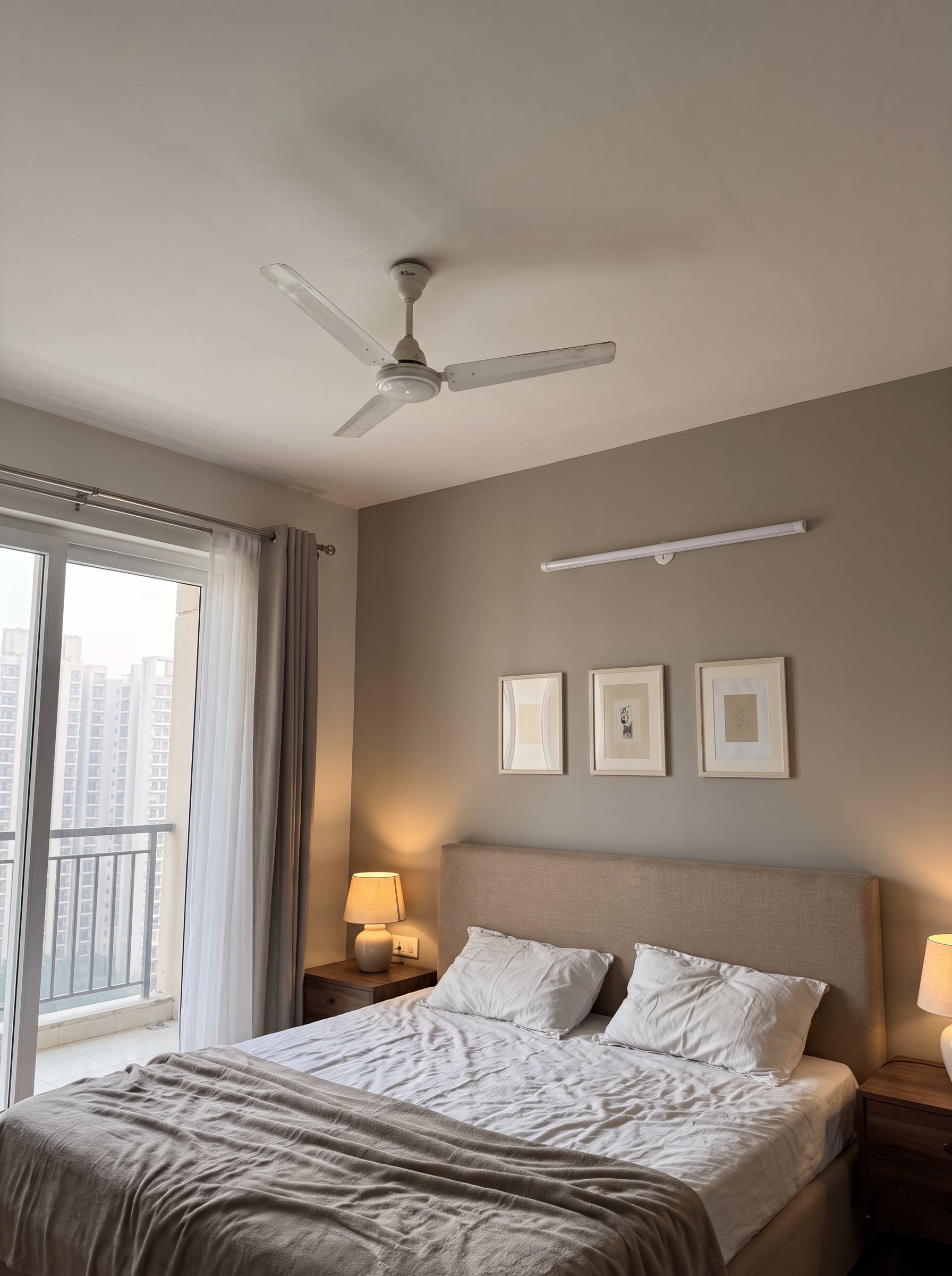 Bedroom with a plain white ceiling, ceiling fan and wall-mounted tube light.